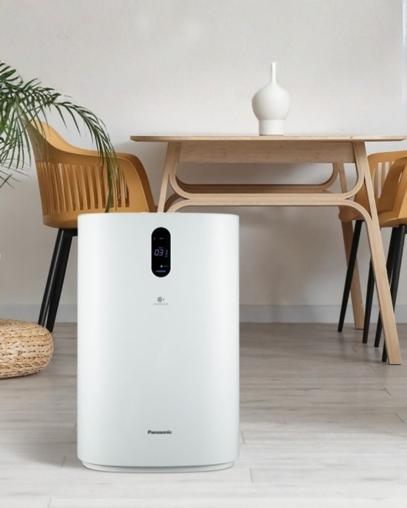 Panasonic Nanoe X air purifier placed beside a wooden table and chair.