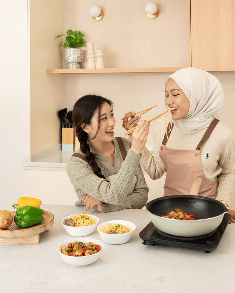 Two women cooking and tasting food using a Tefal matcha frypan.
