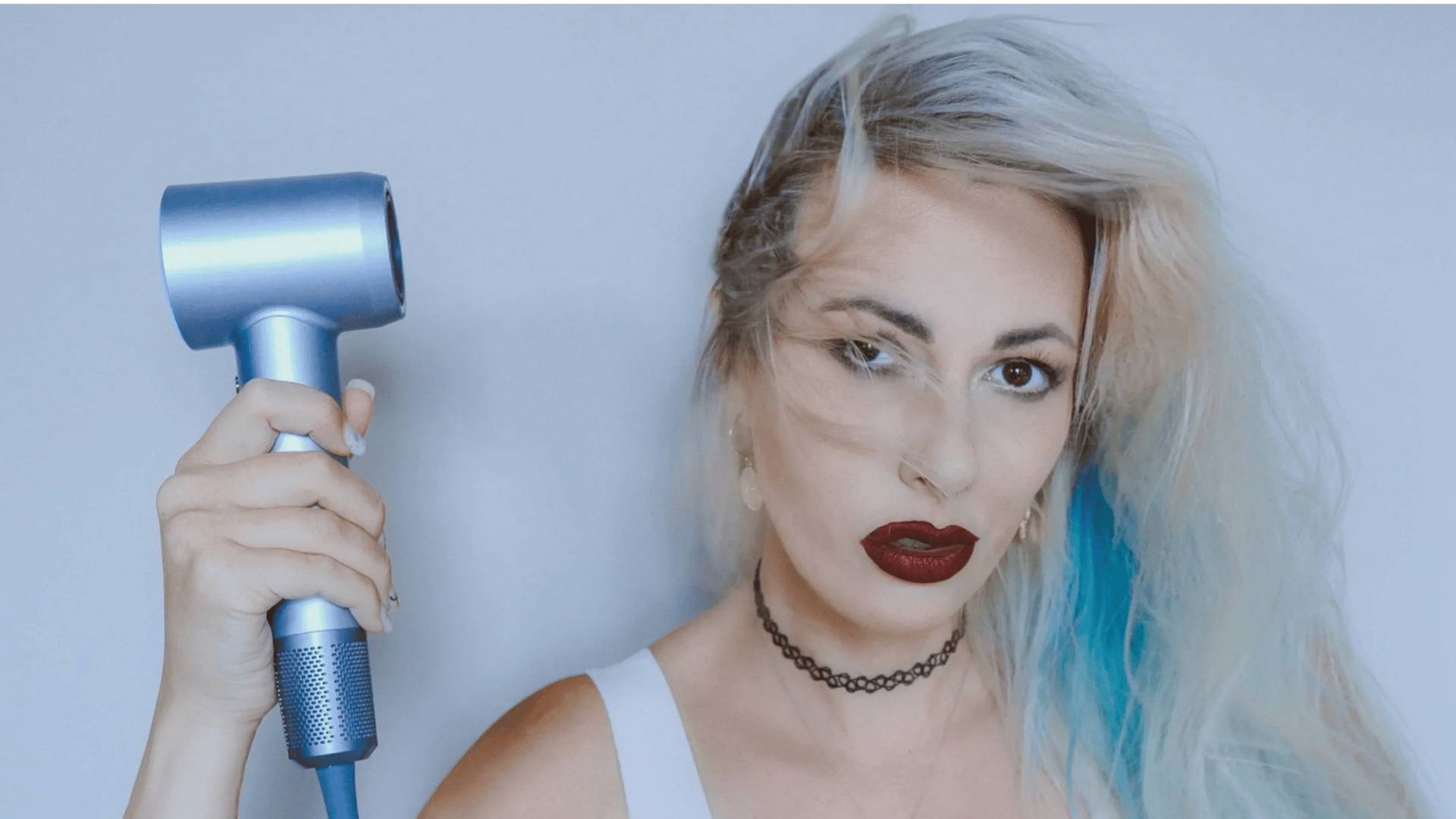 Woman holding a blue Laifen hair dryer with frizzy hair.