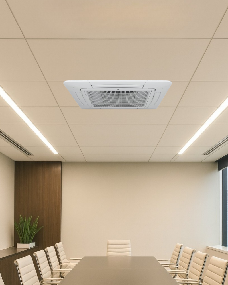 Ceiling cassette air conditioner installed in a modern meeting room with a long conference table and linear LED ceiling lights.
