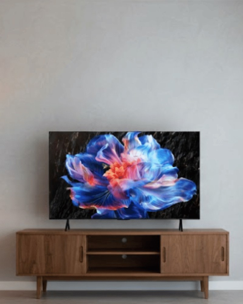 TCL 4K HDR TV on a wooden TV console in a bright, minimalist living room, displaying a vivid, colourful, flower-like abstract image.